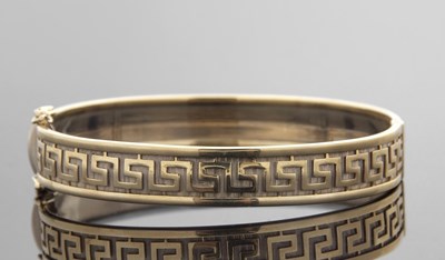 Lot 377 - A 9ct Greek key decorated hinged bangle, the...