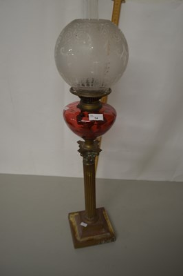 Lot 34 - An oil lamp with brass base and red tinted...
