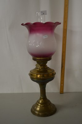 Lot 9 - A brass based oil lamp with cranberry tinted...