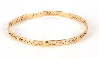 Lot 194 - A bangle stamped 750, the 5mm wide pierced...