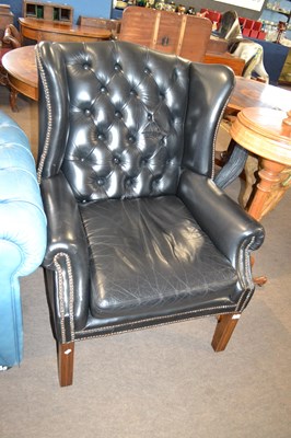 Lot 580 - A black buttoned leather upholstered wing...