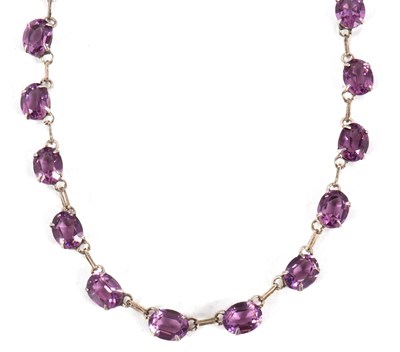 Lot 222 - A purple stone riviere necklace, the oval...