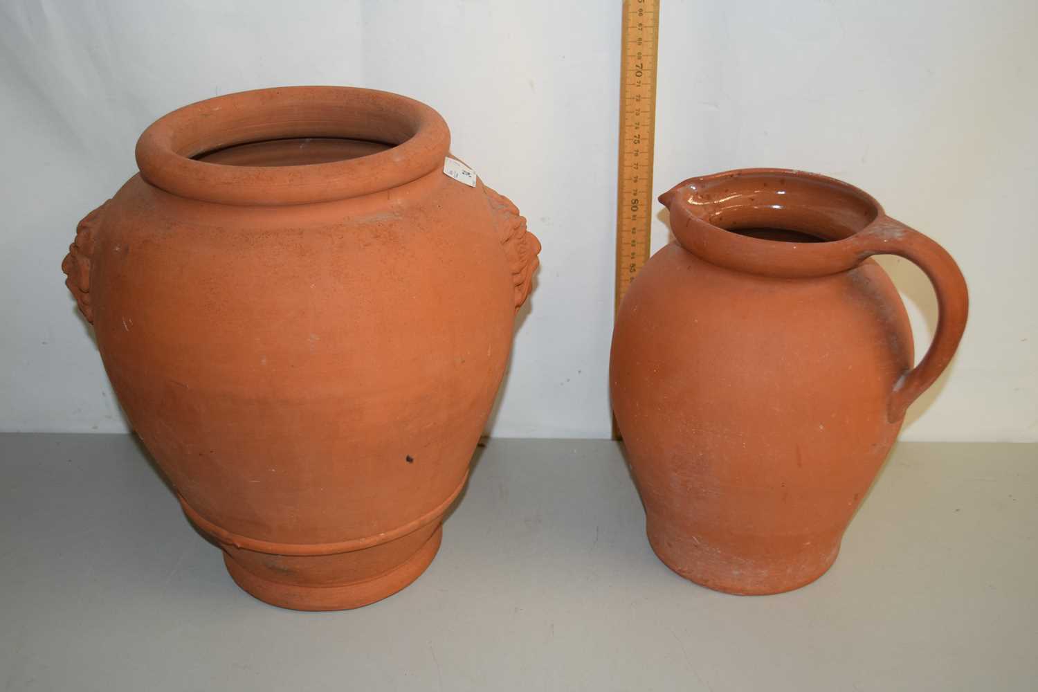 Lot 34 - A terracotta ovoid formed jar with mask...