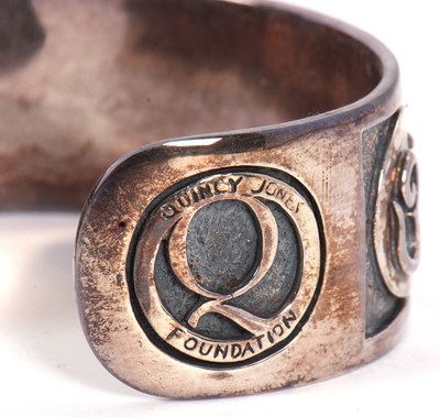 Lot 116 - A 'Quincy Jones Foundation' silver cuff, the...