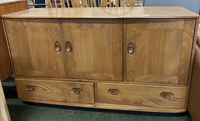 Lot 203 - An Ercol light elm sideboard with three doors...
