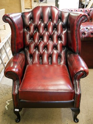 Lot 571 - Red leather Chesterfield wing chair raised on...