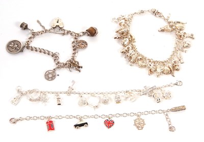 Lot 419 - Four silver charm bracelets, set with a...