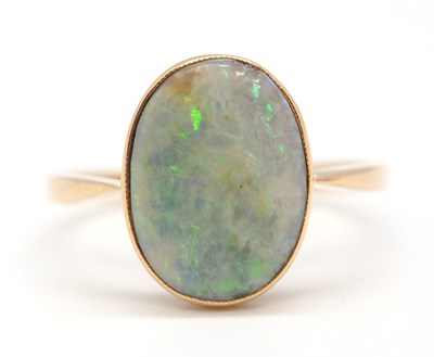 Lot 34 - An opal ring, the oval opal cabochon in collet...