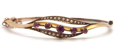 Lot 117 - A 9ct pink stone and seed pearl bangle, the...