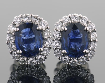 Lot 409 - A pair of sapphire and diamond cluster...