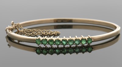 Lot 438 - A 9ct emerald bangle, the upper half set with...