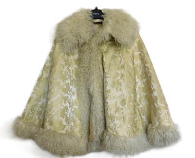 Lot 14 - A cream and gilt brocade fur trimmed cape, by...