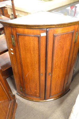 Lot 603 - A George III oak bow front two door wall...