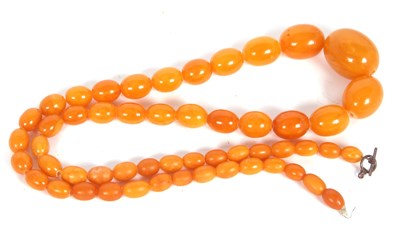 Lot 243 - A butterscotch amber bead necklace, the oval...