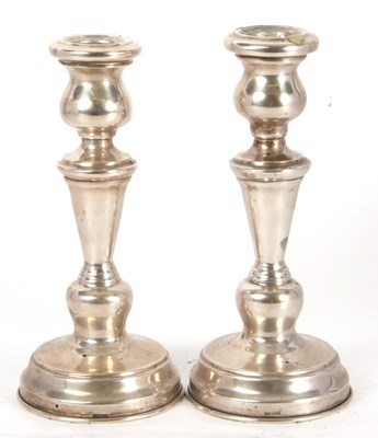 Lot 17 - A pair of white metal candlesticks having urn...