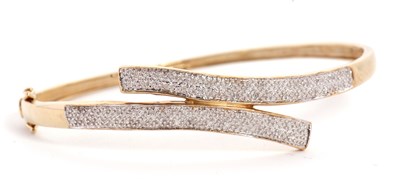 Lot 101 - A diamond bangle, the hinged crossover style...