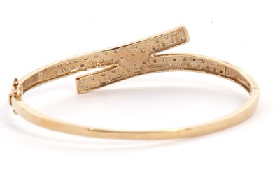 Lot 101 - A diamond bangle, the hinged crossover style...