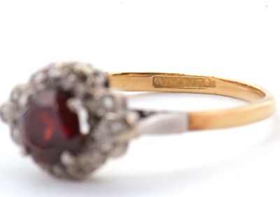 Lot 21 - A garnet and diamond ring, the central round...