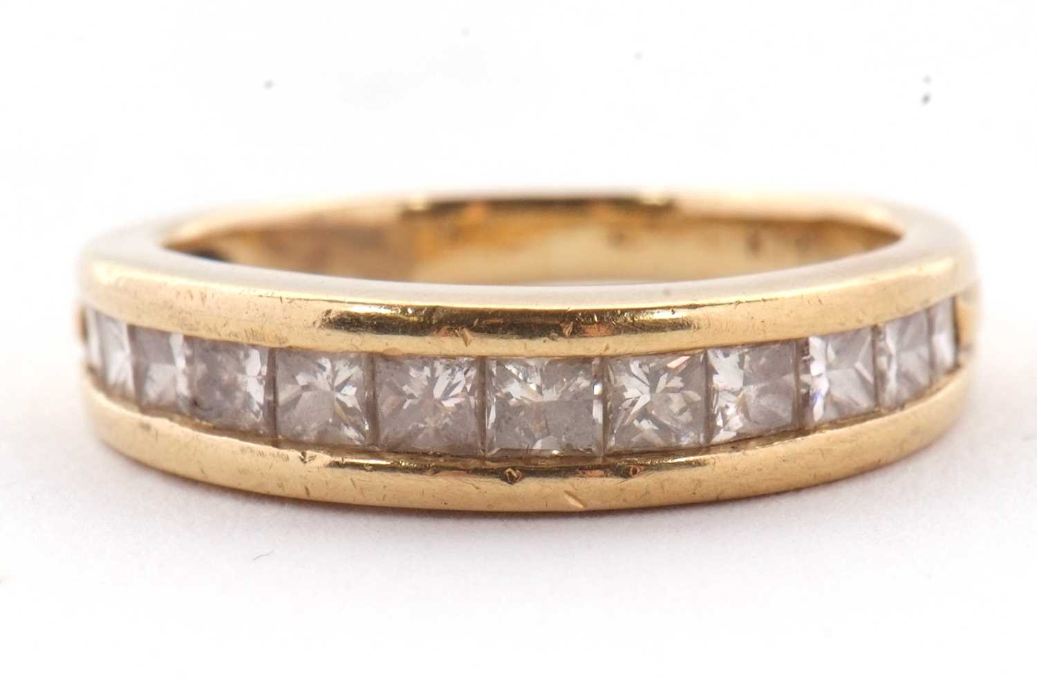 Lot 24 - A diamond ring, the channel set graduated...