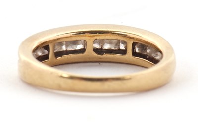 Lot 24 - A diamond ring, the channel set graduated...