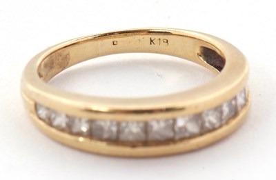 Lot 24 - A diamond ring, the channel set graduated...
