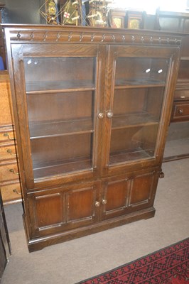 Lot 411 - An Ercol dark elm bookcase cabinet with two...