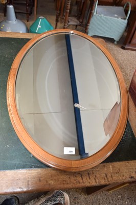 Lot 309 - An oval bevelled wall mirror in light oak frame