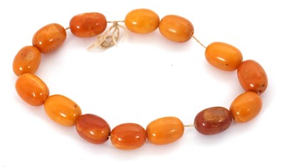 Lot 259 - A string of butterscotch amber beads, the oval...