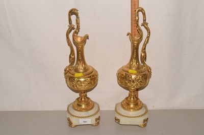 Lot 101 - A pair of gilt metal ewers raised on polished...