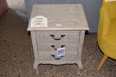 Lot 297 - An as new limed finish three drawer bedside...