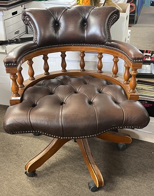 Lot 424 - A leather upholstered desk chair with curved...