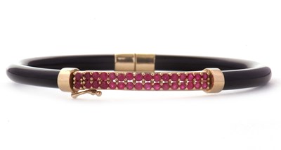 Lot 82 - A 9ct ruby bangle, the black gloss finish...