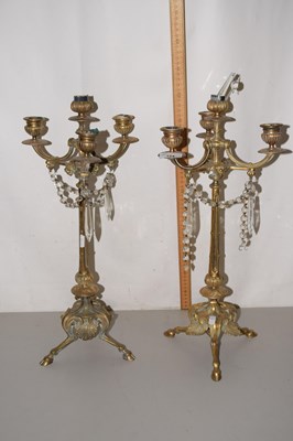 Lot 124 - A pair of brass candelabra on tripod bases...