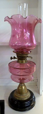 Lot 343 - Oil lamp with cranberry tinted frilled shade...