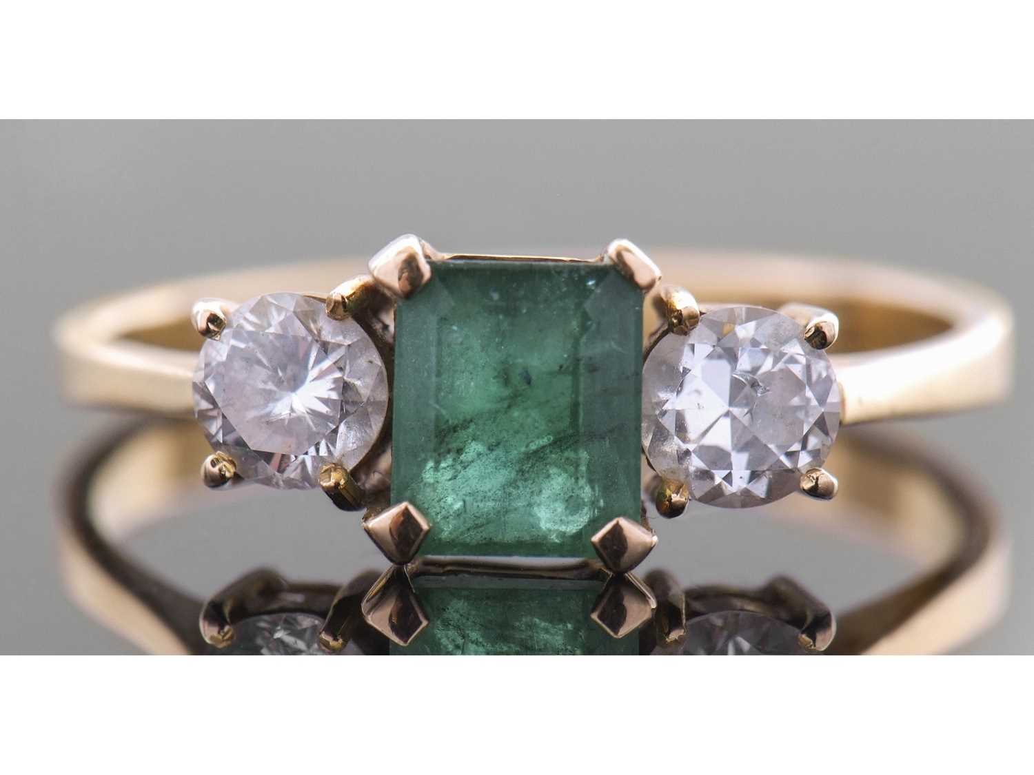Lot 190 - Emerald and diamond three stone ring centring...
