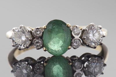 Lot 317 - Emerald and diamond ring centring an oval cut...
