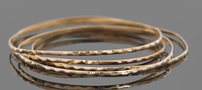 Lot 400 - Four mid-grade yellow metal bangles with...