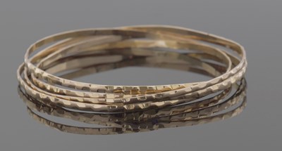 Lot 401 - Four mid-grade yellow metal bangles with...