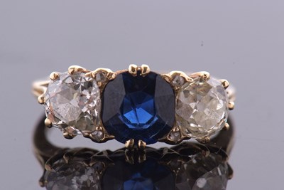 Lot 389 - A three stone sapphire and diamond ring, the...