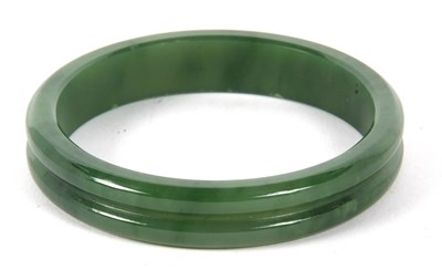 Lot 207 - A nephrite bangle, the 14mm wide bangle with a...